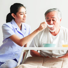 caregiver helping senior man eat