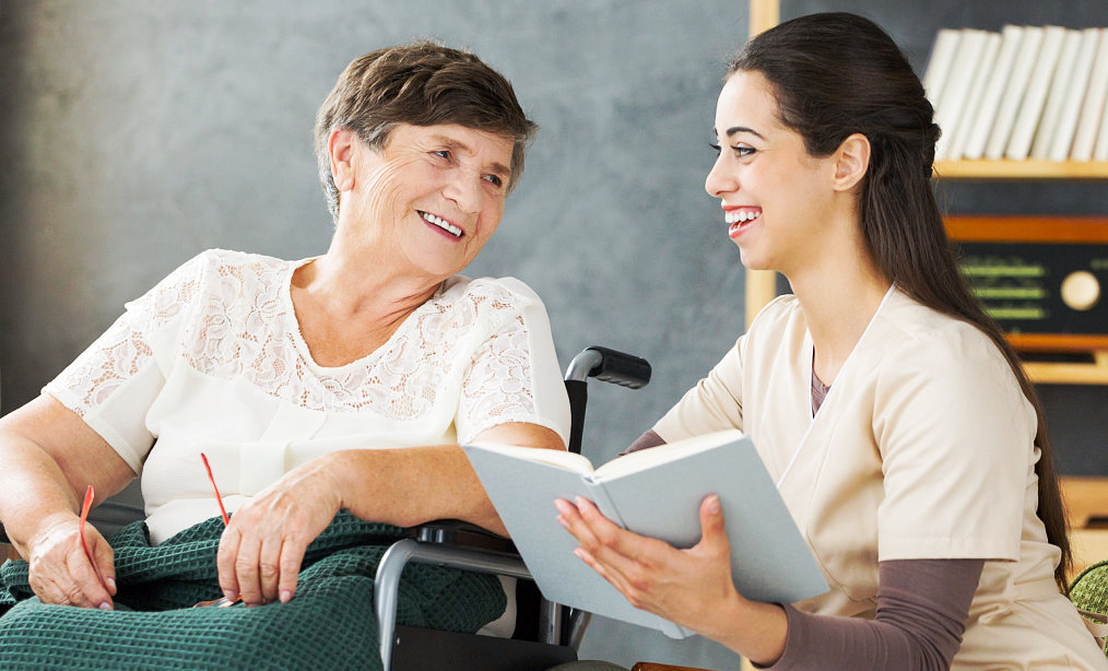 caregiver reading a book for a senior woman