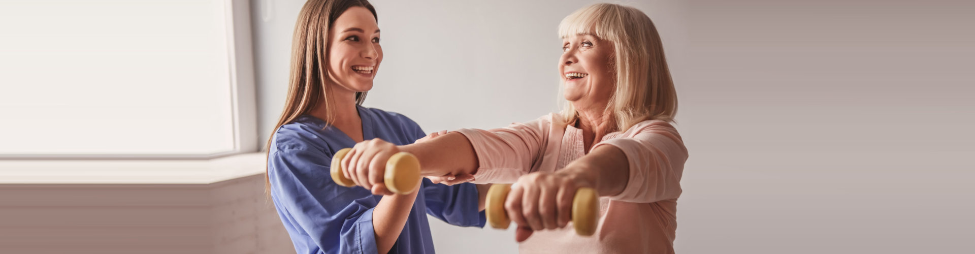 caregiver helping senior woman do her exercise
