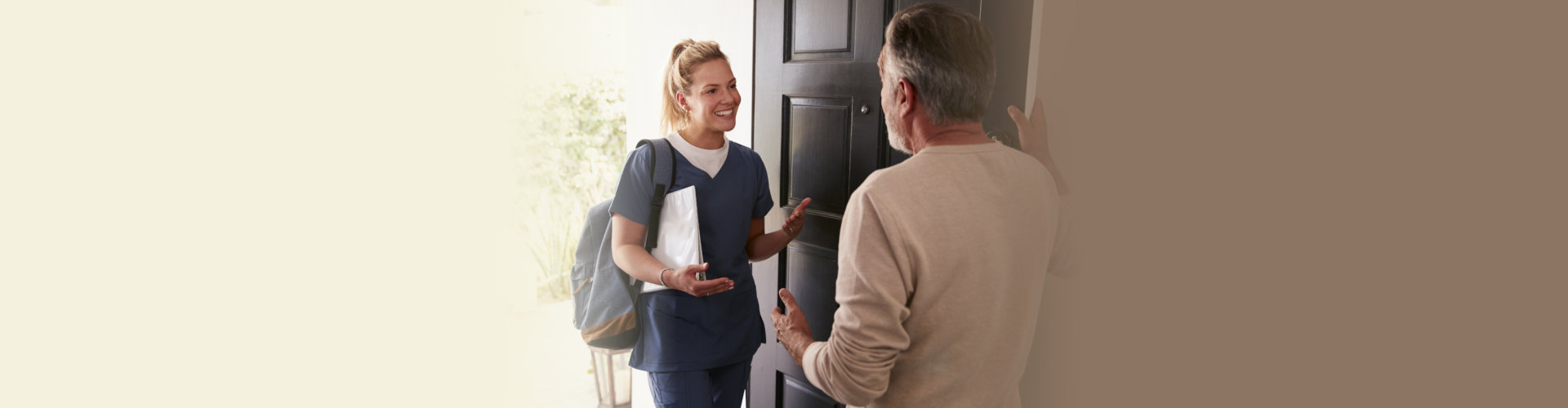 a man opening his front door to a healthcare worker making a home health visit